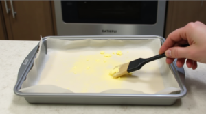 Baking pan lined with parchment paper, greased with butter, ready for brownie batter.
