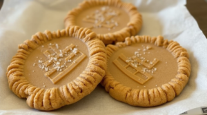 Three keto peanut butter cookies with a fork-pressed pattern, arranged on parchment paper.